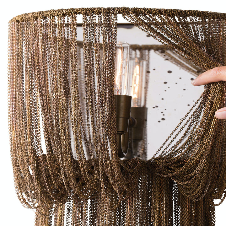 Close-up of antique brass light fixture with metallic fringe.