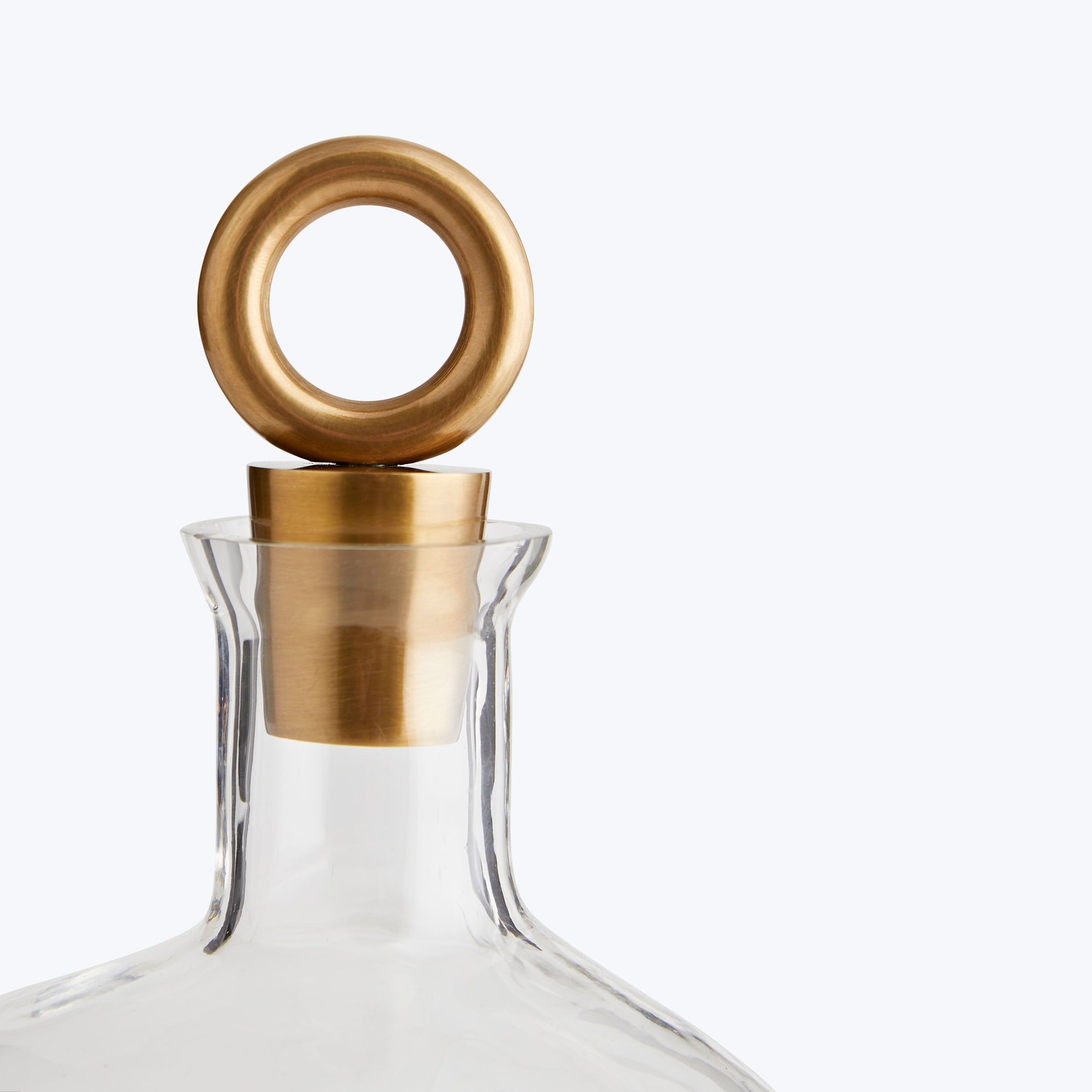 Close-up of a clear glass bottle with a gold stopper.