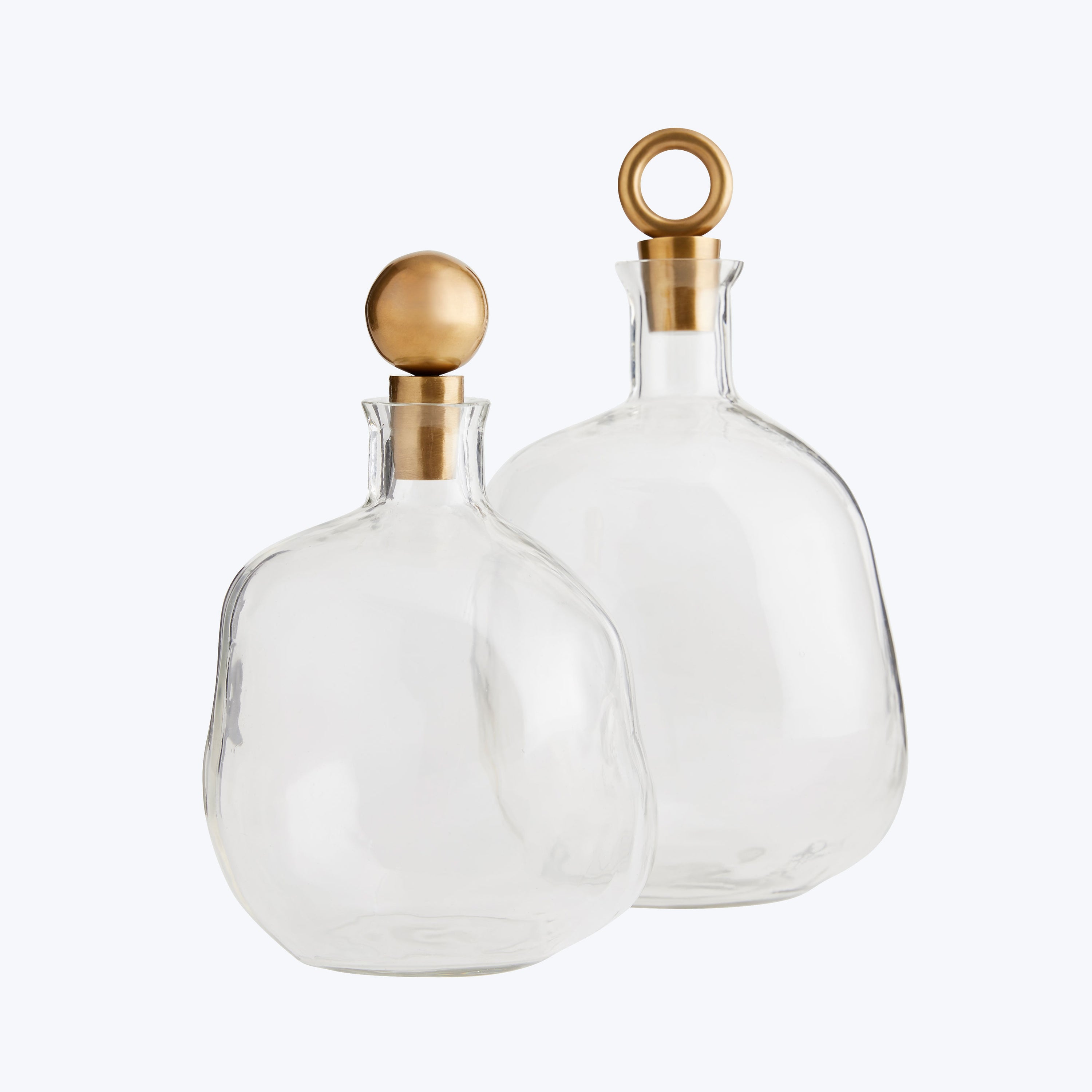 Two elegant glass bottles with golden decorative stoppers on white.