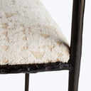 Close-up of a luxurious white upholstered chair with metal frame.
