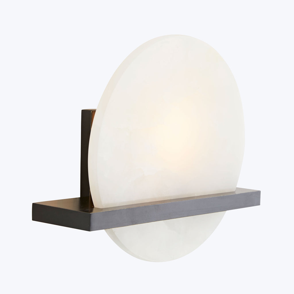 Minimalist wall-mounted light fixture with translucent, warm-glowing round shade.