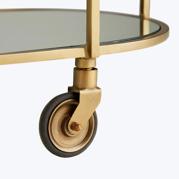 Close-up of a brass caster wheel on a sleek serving cart.