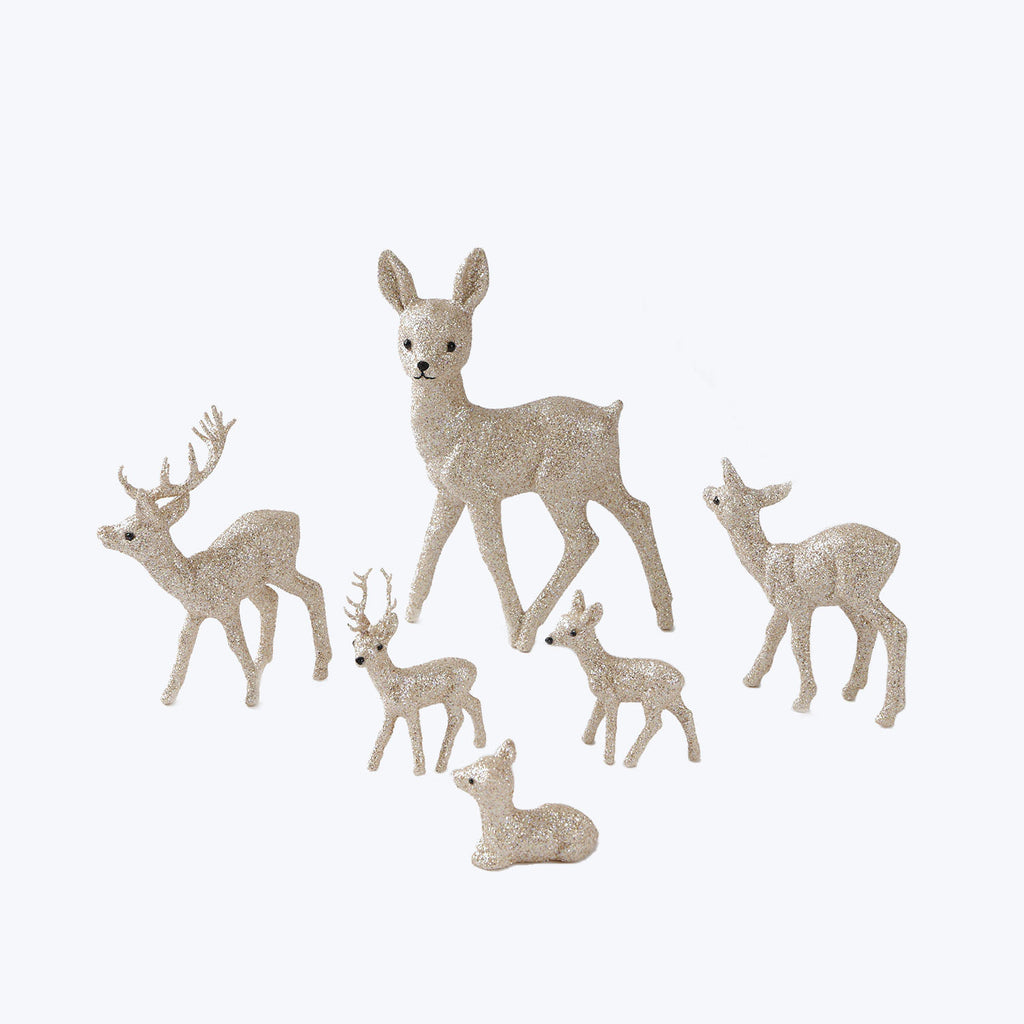 Seven glittery deer figurines in various sizes and poses. Festive decor.