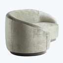 Modern armchair with rounded shape and velvet upholstery in pale green or gray.