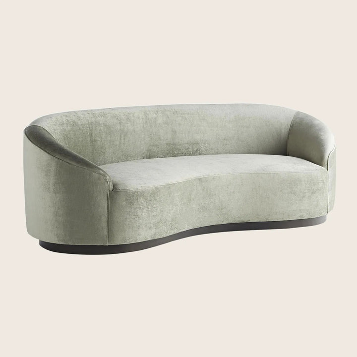 Modern-style curved sofa upholstered in soft, pale green velvet fabric