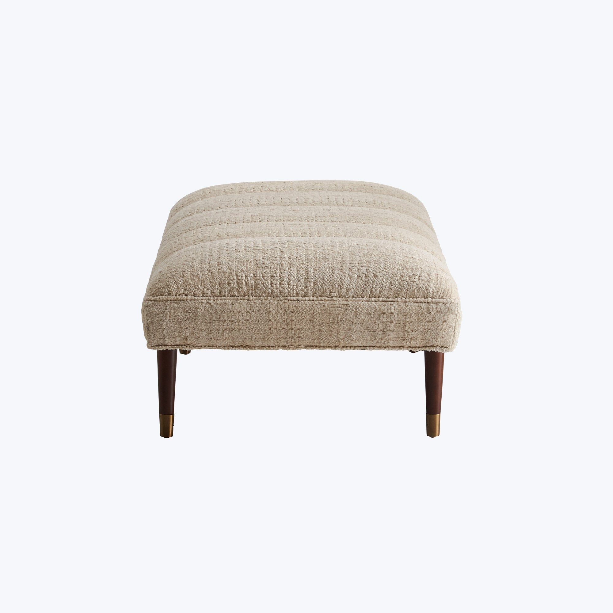 Elegant cream ottoman with textured upholstery and wooden tapered legs.