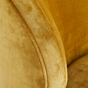 Close-up of upholstered furniture in yellow-gold linen-like fabric with fine grain texture and detailed piping.