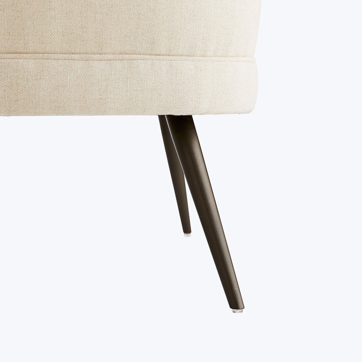 Close-up of a light beige upholstered chair with tapered legs.