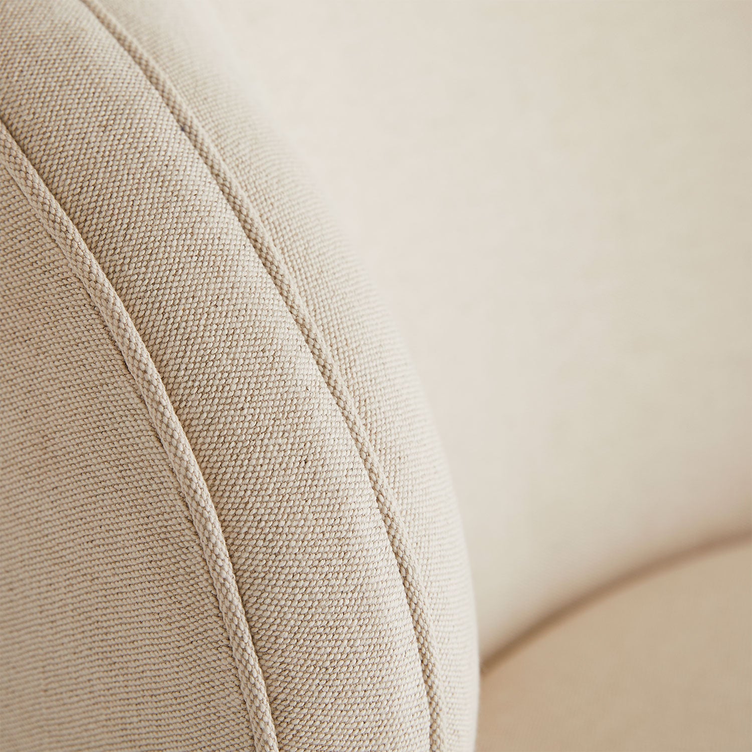 Close-up of textured beige fabric with prominent weave pattern and seam detail.