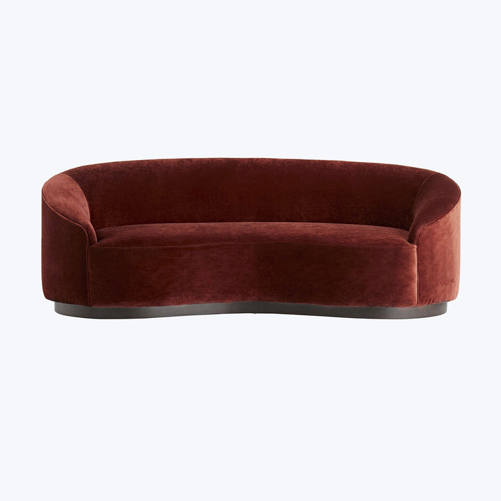 Elegant burgundy crescent sofa with plush velvet-like texture and contemporary design.