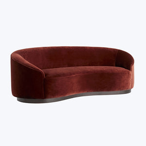 Elegant and contemporary curved sofa in plush burgundy velvet.