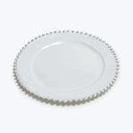 Elegant white plate with textured edge design on white background.