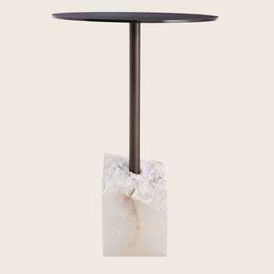 Contemporary side table with dark round top, metallic support, stone base.