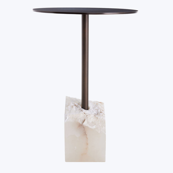 Contemporary side table with dark round top, metallic support, stone base.