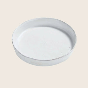 Distressed white ceramic plate with worn edge, rustic appearance.