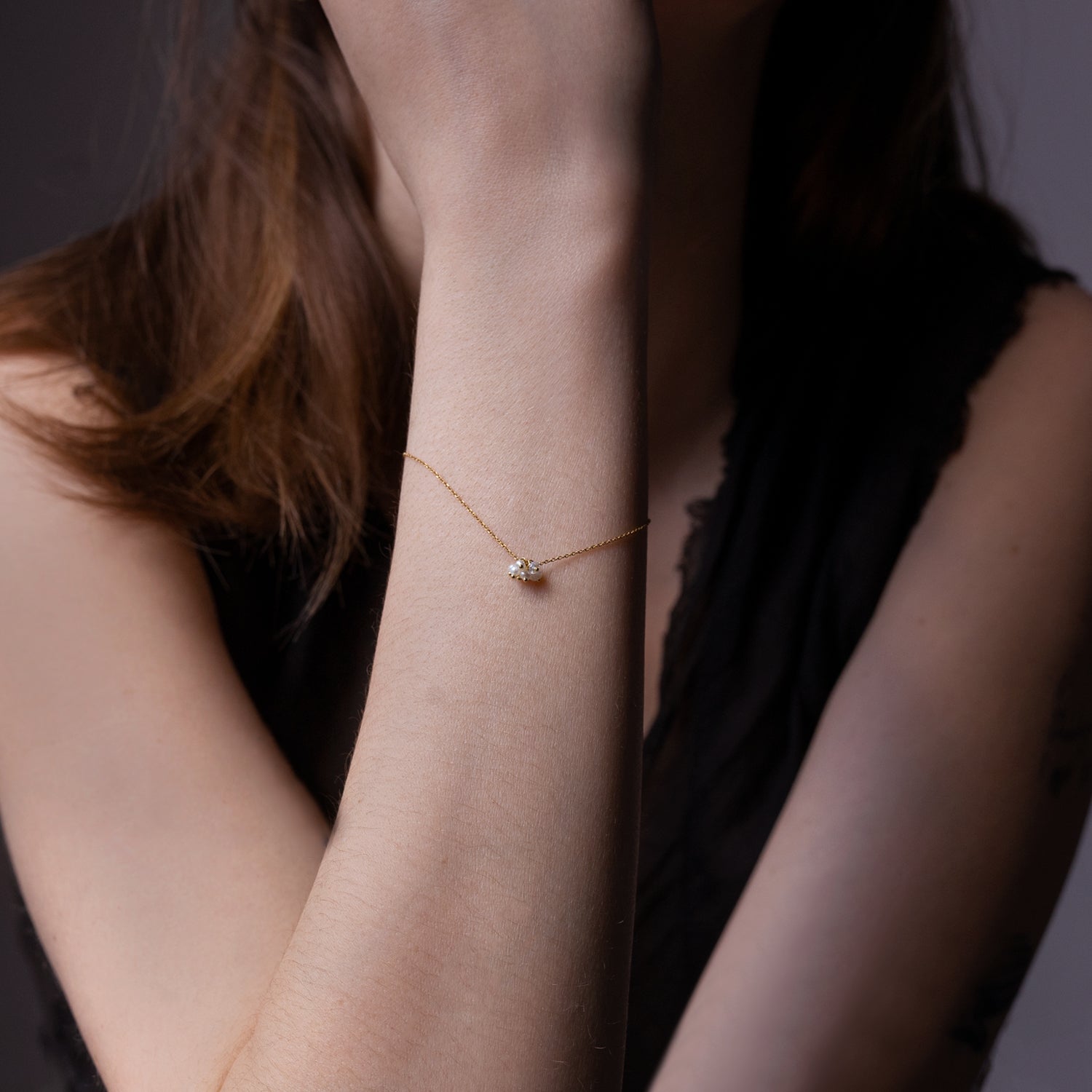 Elegant gold bracelet with gem on woman's delicate arm.