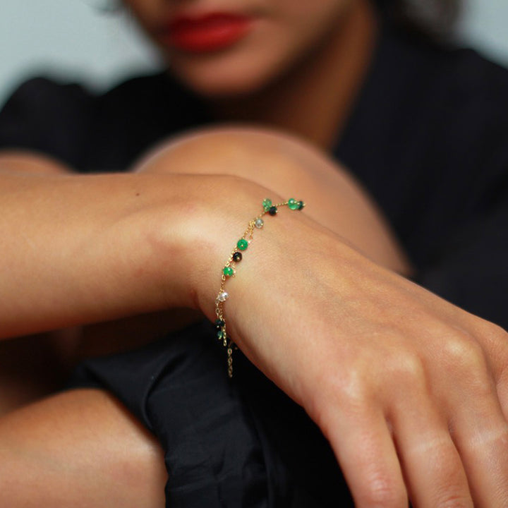 Dainty green gemstone bracelet on elegant wrist, fashionable accessory.