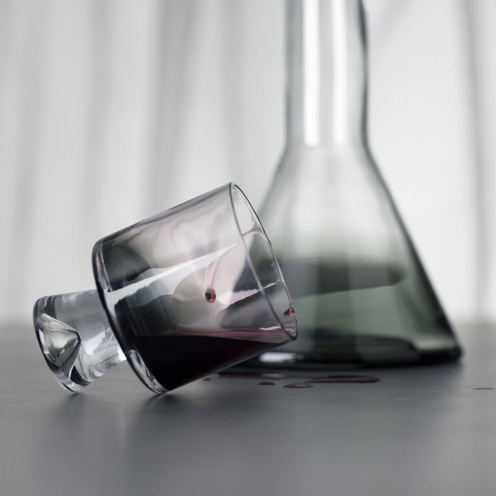 Spilled red wine from tipped-over glass on reflective surface.