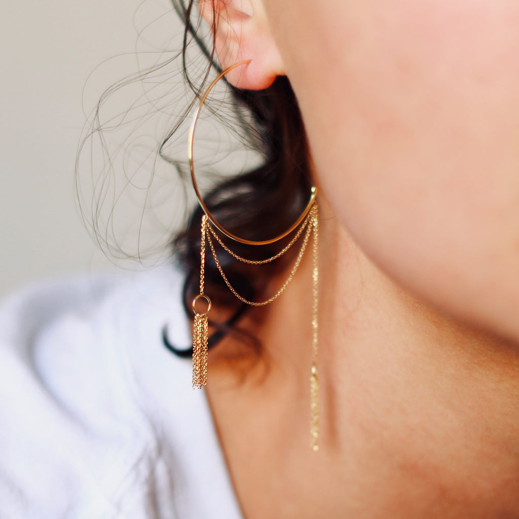 Close-up of person wearing intricate gold earring with elegant chains