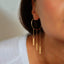 Stylish woman showcasing large gold hoop earring with cascading chains.