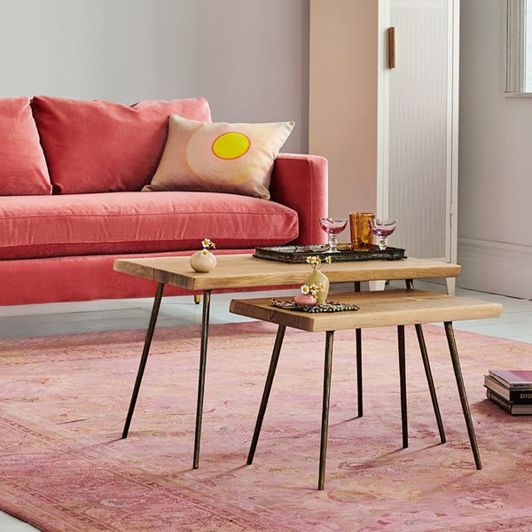 Cozy meets modern: A well-styled interior scene with a pink velvet sofa, nesting coffee tables, and thoughtful design elements.