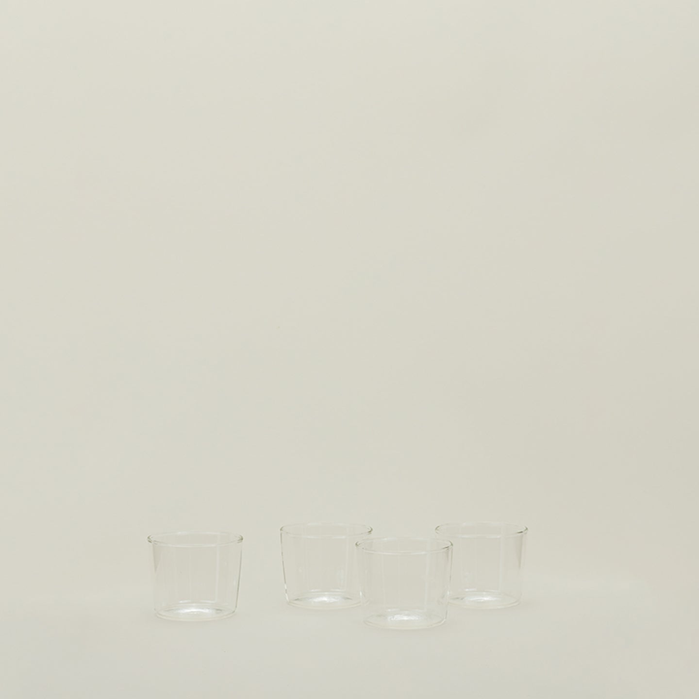 Minimalist arrangement of empty glass cups on neutral background.