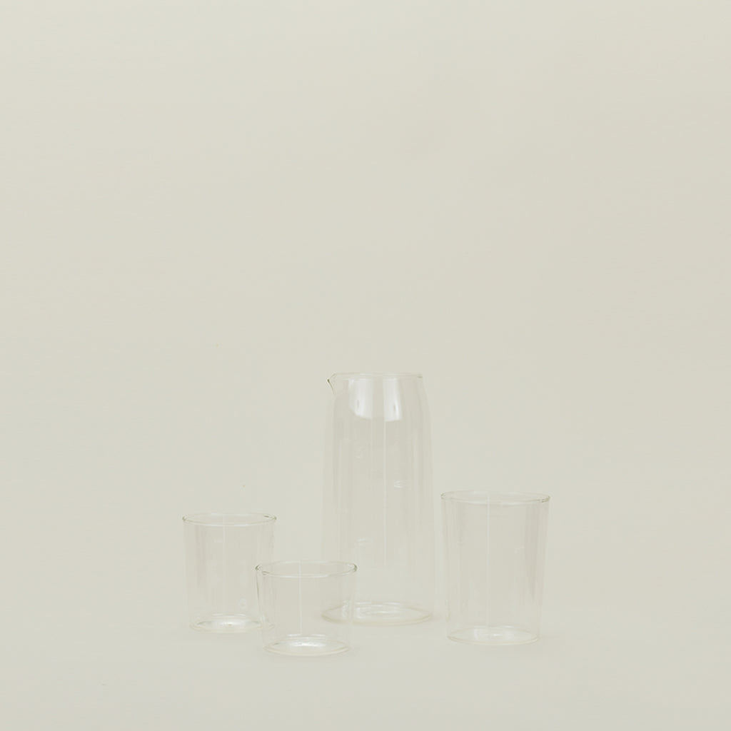 A minimalist arrangement of four glass vessels against a light background.