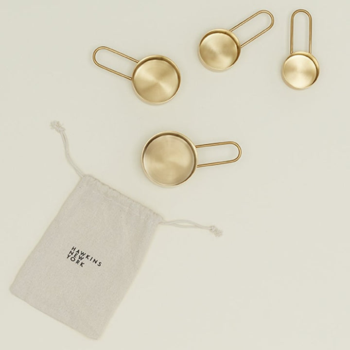 Four elegant golden measuring spoons neatly organized in descending sizes.