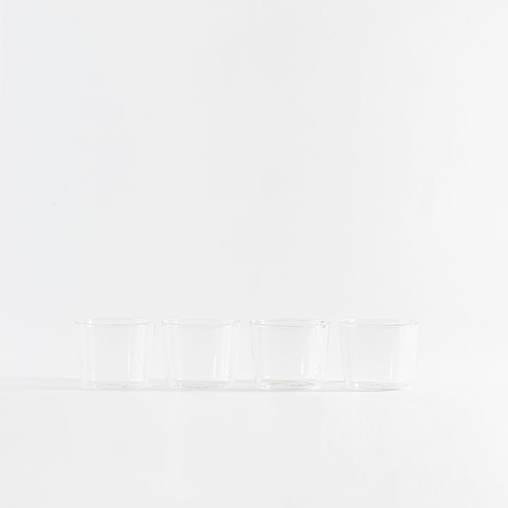 Four sleek glass cups displayed in a minimalist arrangement.