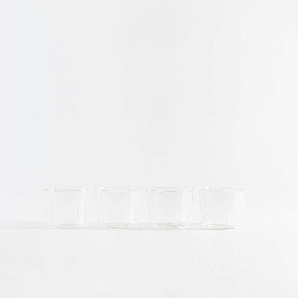 Four sleek glass cups displayed in a minimalist arrangement.