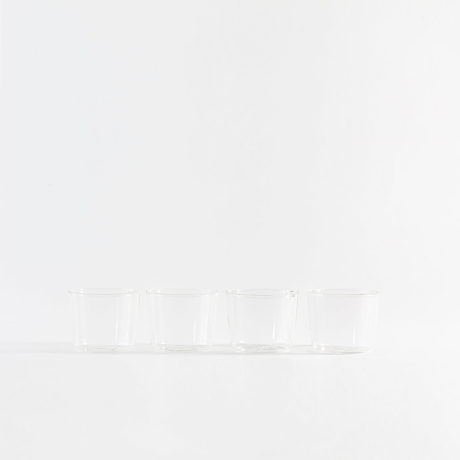 Four sleek glass cups displayed in a minimalist arrangement.