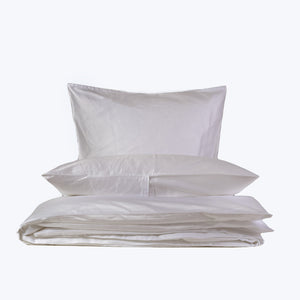 Set of fluffy pillows and folded pink bedding on display. - hover