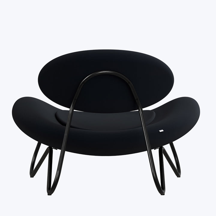 Modern, sculptural chair with sleek black design and elegant profile.