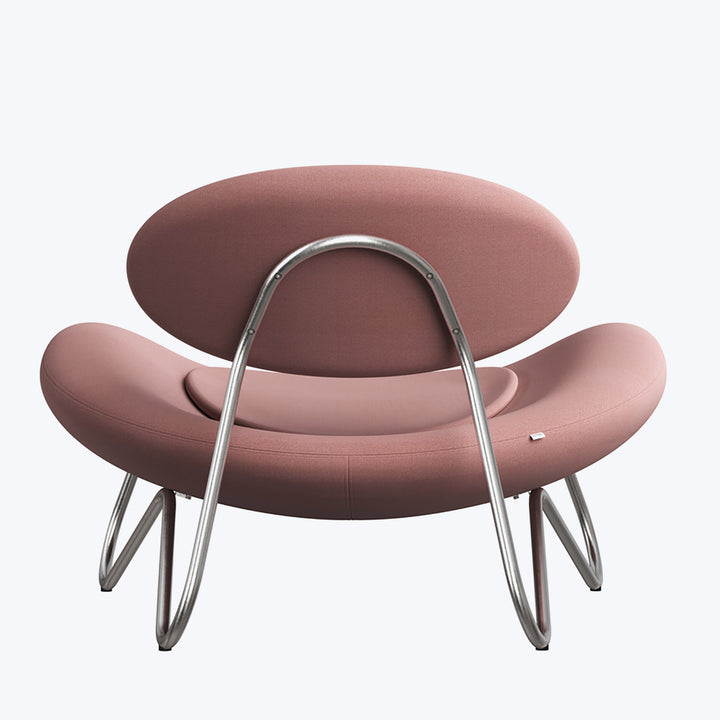 Modern armchair with unique rounded shape and dusky pink cushions.