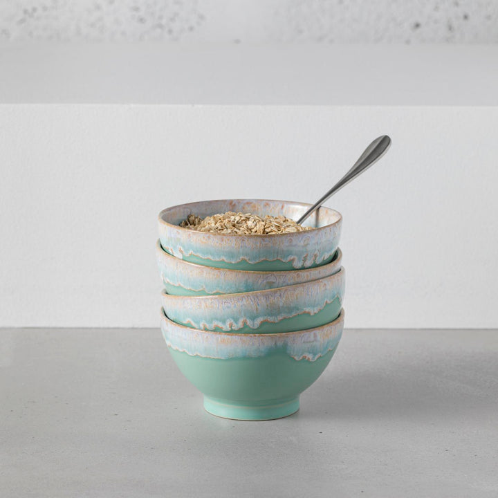 Four ceramic bowls with a rustic design, filled with oatmeal.