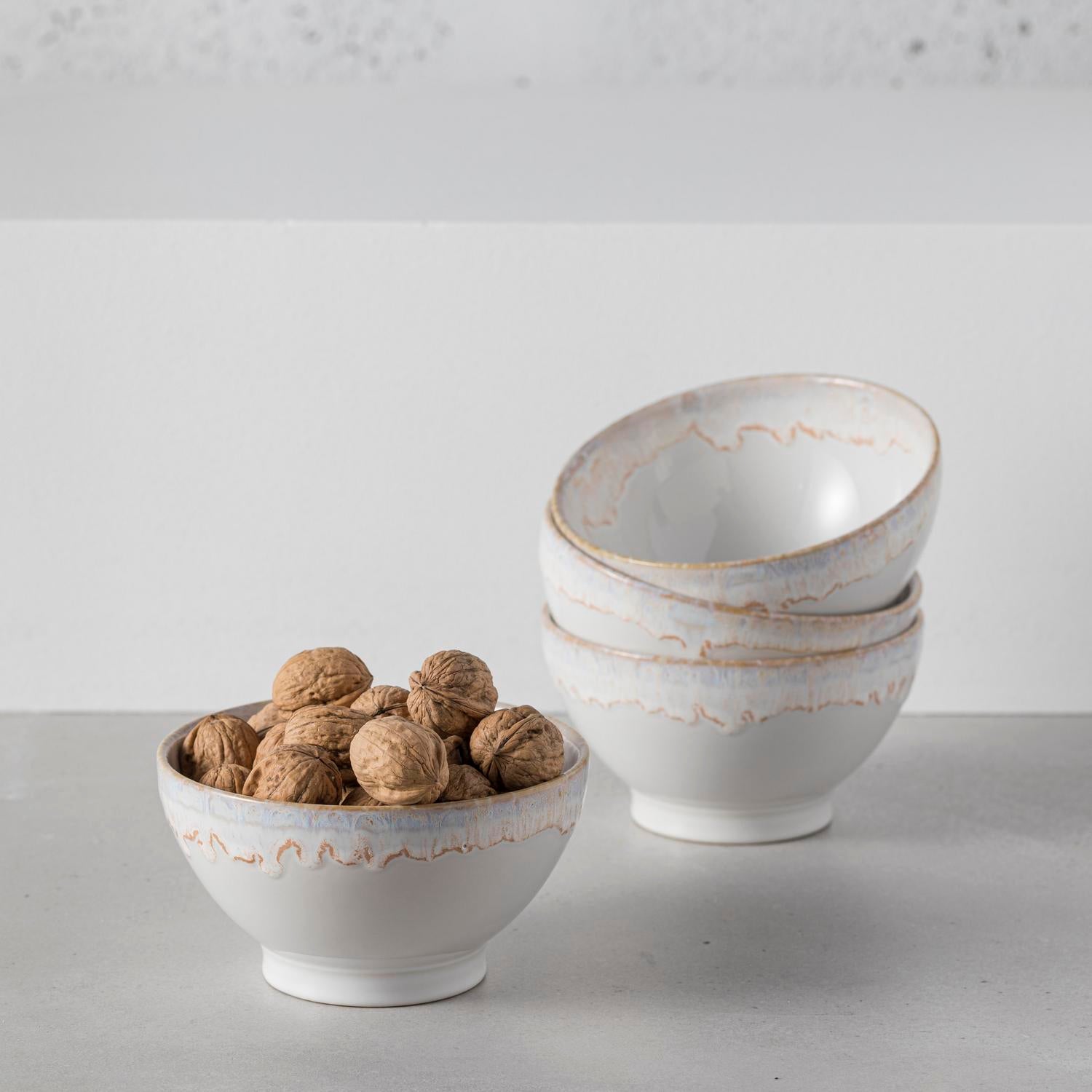 Minimalistic ceramic bowls with walnuts on rustic two-tone backdrop.