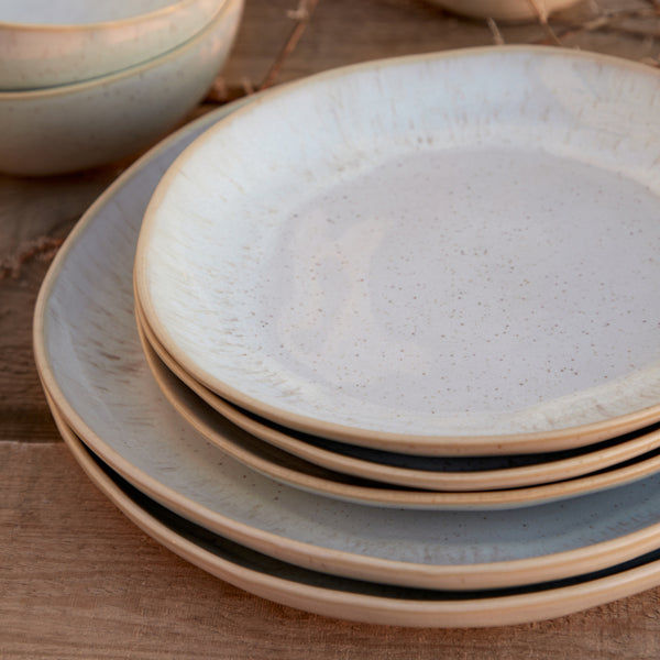 Rustic ceramic plates with speckled pattern arranged on wooden surface.