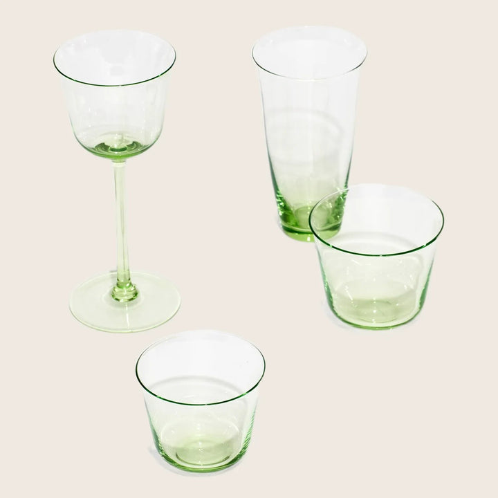 Green-tinted glassware set on white background, includes wine and tumblers.