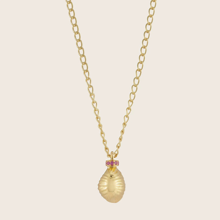 Luxurious gold necklace with textured shell pendant and pink gemstones.